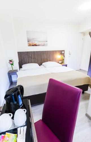 a bedroom with a bed and a table with a purple chair at Pension Altes Backhaus in Herzogenaurach