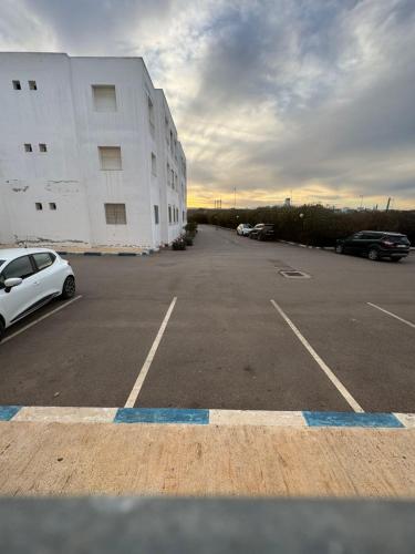 ein Parkplatz mit vor einem Gebäude geparkten Autos in der Unterkunft Skhirate-plage in Skhirat