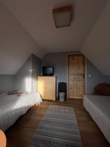 a attic bedroom with two beds and a tv at Pod Cisowcem in Sromowce Wyżne