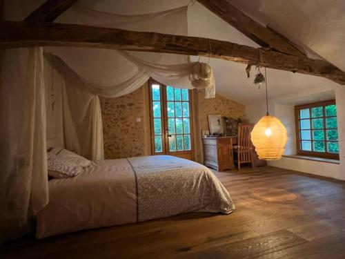 une chambre avec un lit dans une pièce avec des fenêtres dans l'établissement Bel appartement T2 dans maison typique du Périgord, à Rouffignac-Saint-Cernin-de-Reilhac