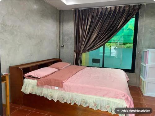a bedroom with a bed with a large window at Baan Khun Ya Sukhothai Old City in Sukhothai