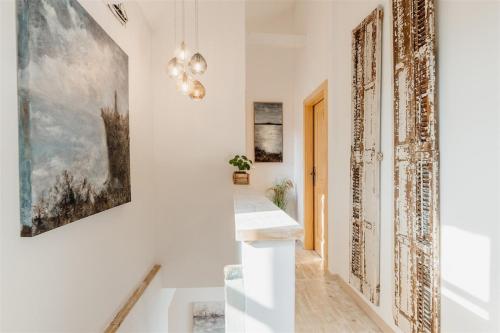a hallway with white walls and a staircase with artwork at Villa pero -an artists home in Ždrelac