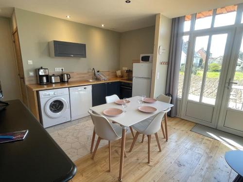 - une cuisine avec une table et des chaises blanches dans la chambre dans l'établissement Gîte Ancien Atelier - chemin de halage, à Muides-sur-Loire