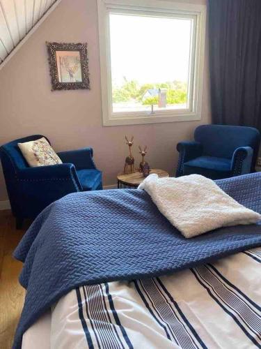 a bedroom with a bed and two chairs and a window at Skalhamn a village seaside in Lysekil
