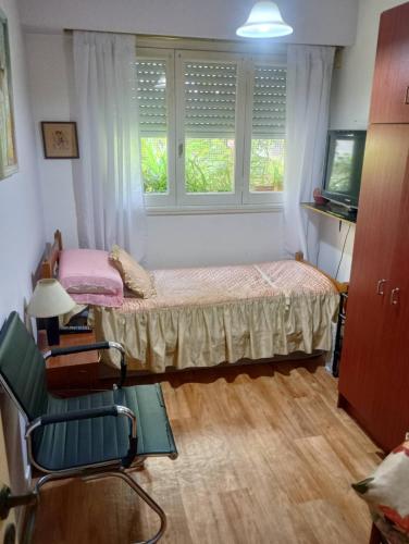 a bedroom with a bed and a chair and two windows at Dpto meli in Mar del Plata