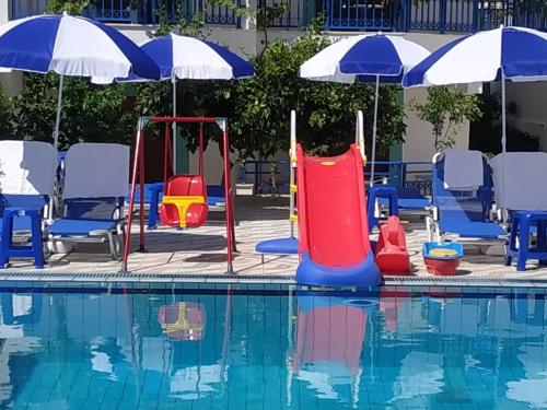 a pool with a water slide and chairs and umbrellas at George Studios Stalis in Stalida