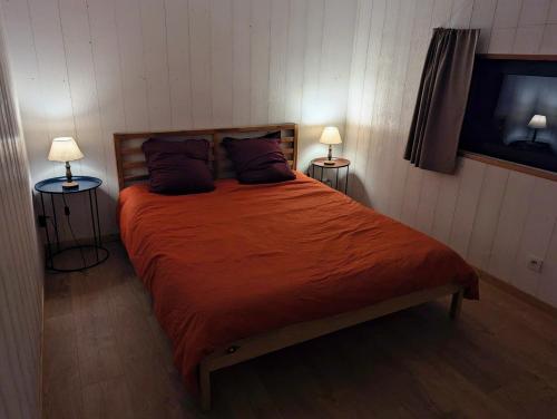 - une chambre avec un grand lit orange et deux lampes dans l'établissement Au Chalet Bourguignon 5, à Salives
