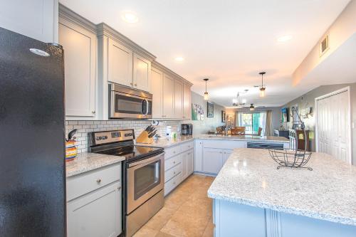 a kitchen with white cabinets and a black refrigerator at Wave n Sea - Deep Water Cove 2B Townhome in Pensacola Beach