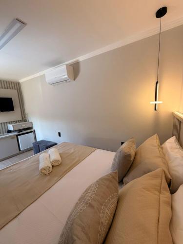 a bedroom with a bed with two pillows and a cross on the wall at Pousada Brilho do Sol in Serra Negra