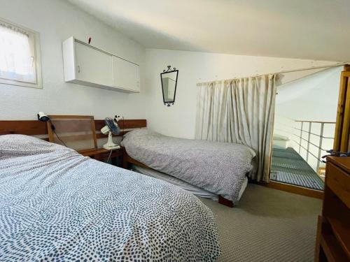 une chambre avec deux lits et une fenêtre dans l'établissement Appart rénové - 4 personnes - piscine - parking, à Fitou