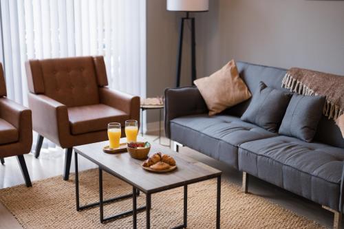 a living room with a couch and two glasses of orange juice at Board Games & Chill Stylish City Apartment in Wolverhampton