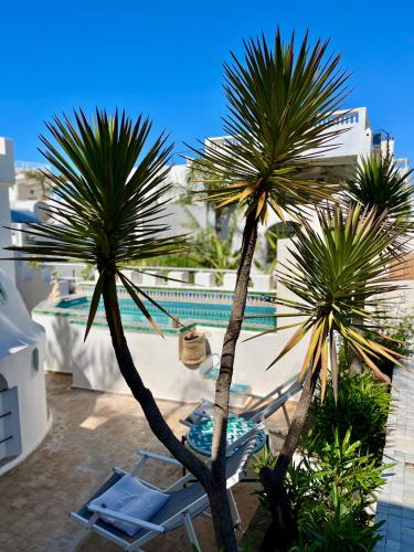 two palm trees and chairs on a patio with a pool at RIAD OASIS D'ASILAH in Asilah