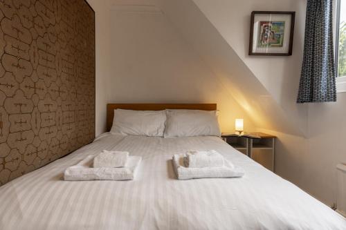 a bedroom with a bed with towels on it at Sandford Meadow Guest House in Oxford