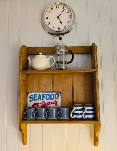 a clock sitting on top of a shelf with mugs at NEW Cosy Gem, Near Beach, Log-Burner, Dog Friendly in East Wittering