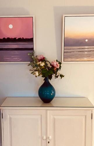 a blue vase with flowers on top of a cabinet at NEW Cosy Gem, Near Beach, Log-Burner, Dog Friendly in East Wittering