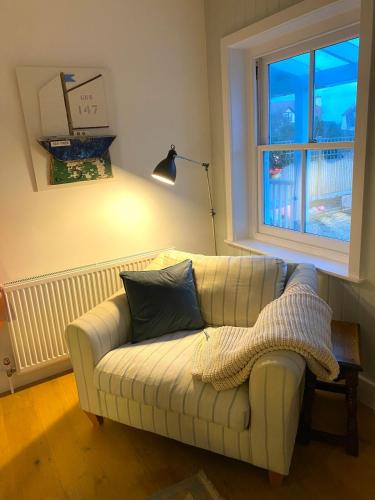 a couch in a living room with a window at NEW Cosy Gem, Near Beach, Log-Burner, Dog Friendly in East Wittering