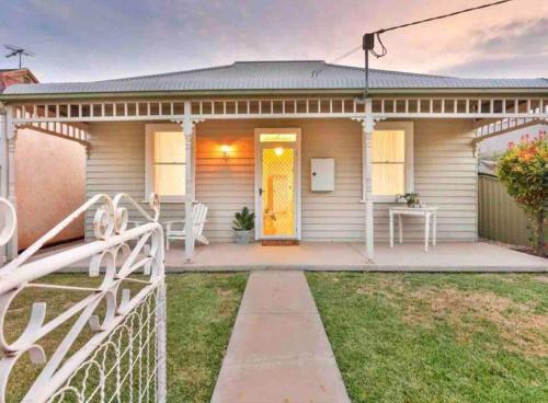 a house with a yellow door and a fence at Schillington Cottage in Mildura