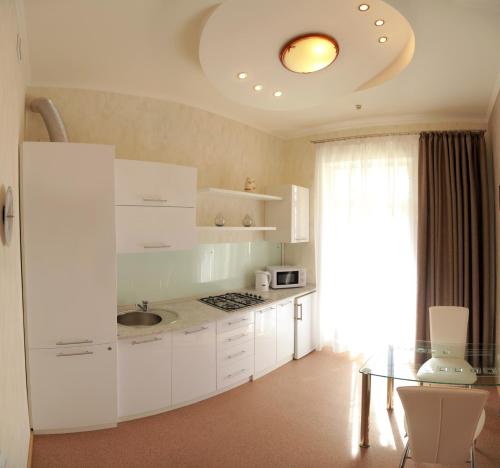 een keuken met witte kasten en een glazen tafel bij VIP on Naberezhnaya str in Nikolayev