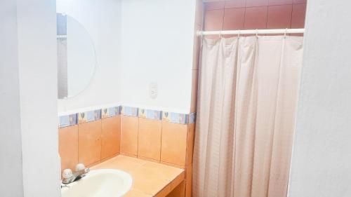 a bathroom with a sink and a shower curtain at Golden Sunset House in Acajutla