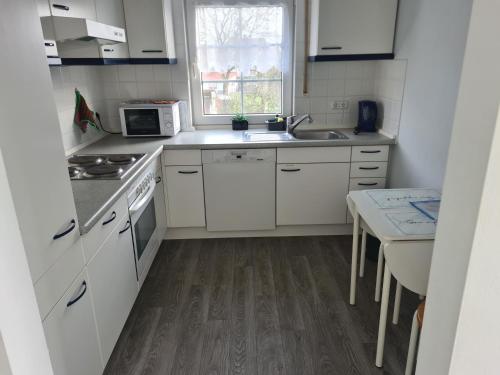 una cucina con mobili bianchi, un lavandino e una finestra di Gemütliches Gästehaus in ruhiger Waldlage a Büdingen