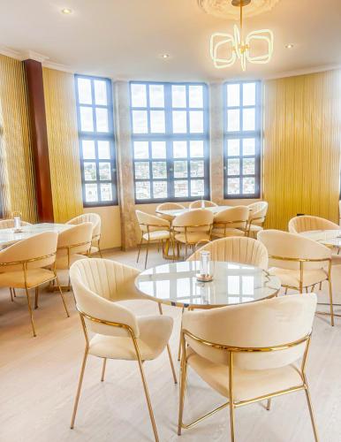 a dining room with tables and chairs and windows at Hotel Sucre in Quito