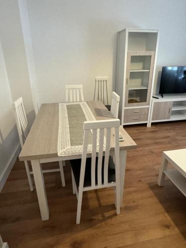 a white dining room table with four chairs and a television at Alojamiento Baeza - Chicharro A in Baeza