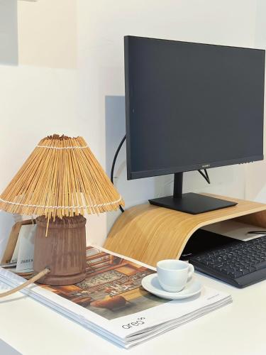 a computer monitor on a desk with a lamp and a keyboard at Downtown A whole house duplex designed for remote work and near metro lapa in Porto