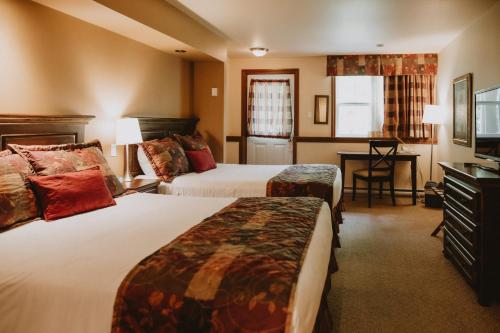a hotel room with two beds and a desk at Auberge du Lac Morency in Saint-Hippolyte