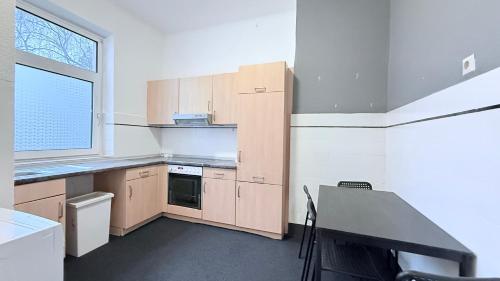 a kitchen with wooden cabinets and a table and a window at Zentrale Monteurwohnung Neumünster mit Küche & WLAN in Neumünster