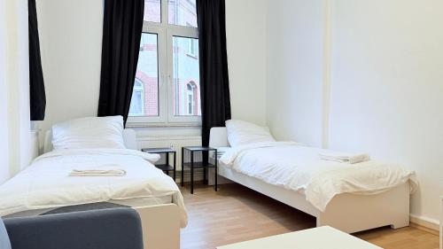 two beds in a room with a window at Zentrale Monteurwohnung Neumünster mit Küche & WLAN in Neumünster