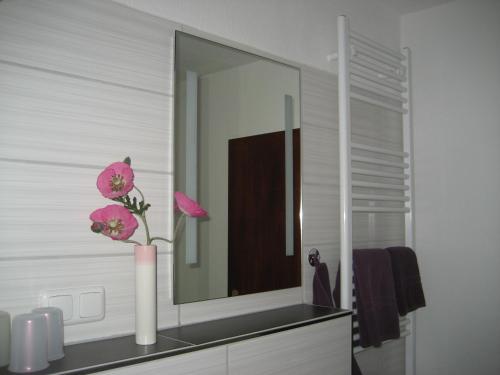 a bathroom with a mirror and a vase with flowers at Ferienwohnung Schneemann in Hohegeiß