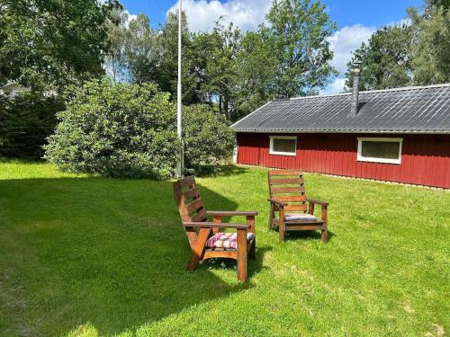 two benches sitting in the grass in front of a red barn at Lake cottage with private pier in Bälinge