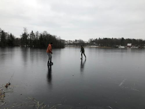 two people are skateboarding on a frozen lake at Lake cottage with private pier in Bälinge