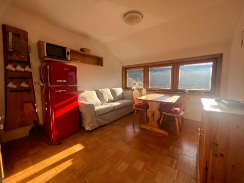 a living room with a red refrigerator and a couch at Apartmaji Katrnjek in Bohinj
