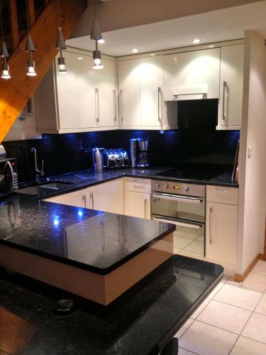 a kitchen with white cabinets and a black counter top at Les Ecureuils Squirrel Lodge in Oz