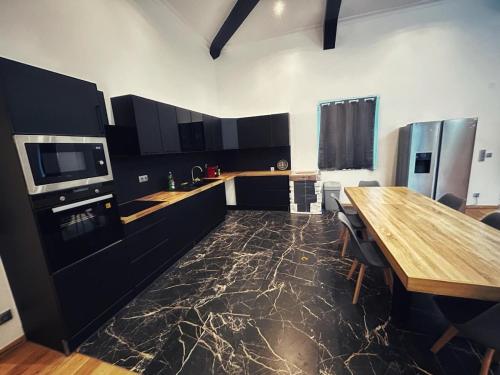 une cuisine avec des armoires noires et une table en bois dans l'établissement Grande maison moderne 5 chambres, à Cherbourg en Cotentin