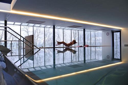 a person in a swimming pool in a room with windows at Seeblick Höhenhotel in Emmetten