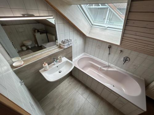 a bathroom with a tub and a sink and a mirror at Ferienwohnung am See in Eriskirch
