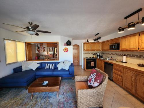 a living room with a blue couch and a kitchen at Beach Eateries Shops 10 min walk Golf view in San José del Cabo