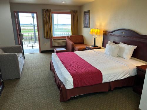 a hotel room with a large bed and a chair at Howards Inn Motel in Eunice