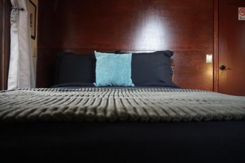 a bed with a wooden headboard and a blue pillow at The Rosemary in Los Angeles