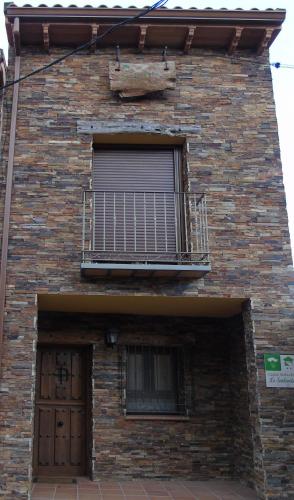 a brick building with a balcony and a door at La Senderuela in Tamajón