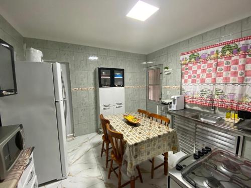 a kitchen with a table with chairs and a refrigerator at Casa simples e aconchegante in Bertioga