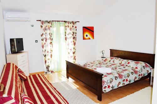 sypialnia z łóżkiem i telewizorem w obiekcie Apartments Darko w Sukošanie