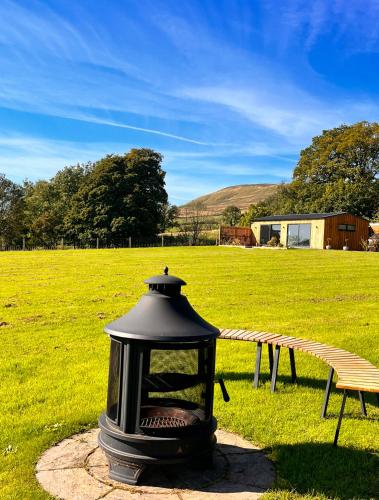 a lantern sitting next to a bench in a field at Cairnfold Cabins in Kilsyth