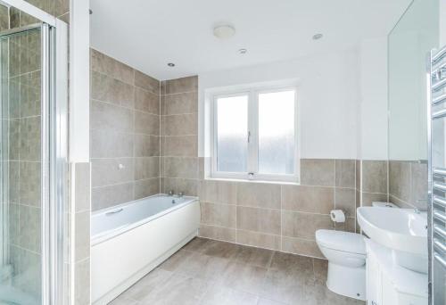 a bathroom with a tub and a toilet and a sink at 5 Bedroom Detached House in Milton Keynes in Bletchley