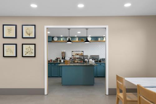 a kitchen with blue cabinets and a table in a room at Country Inn & Suites by Radisson, Near The National Sports Center, Coon Rapids, MN in Coon Rapids