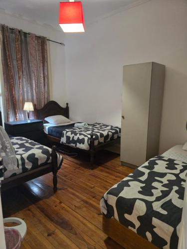 um quarto com 3 camas e um frigorífico em LisBangla Guest House em Lisboa