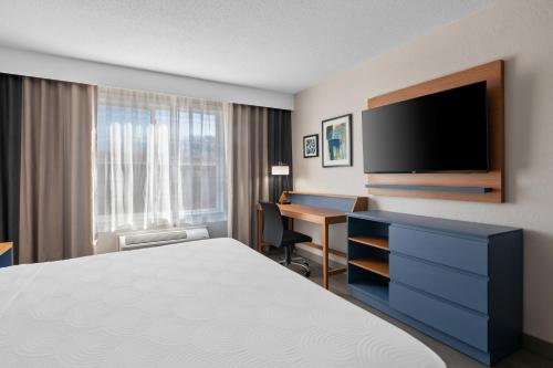 a hotel room with a bed and a desk with a television at Country Inn & Suites by Radisson, Near The National Sports Center, Coon Rapids, MN in Coon Rapids
