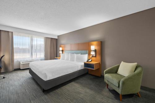 a hotel room with a bed and a chair at Country Inn & Suites by Radisson, Near The National Sports Center, Coon Rapids, MN in Coon Rapids
